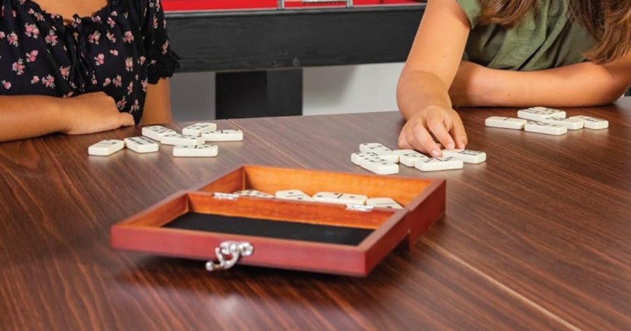 kids playing with dominoes pieces and a wooden storage box in front