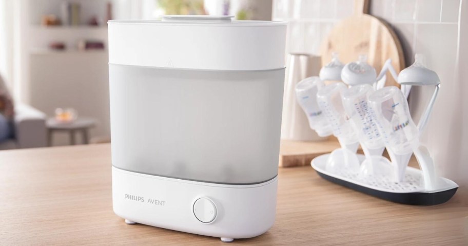 white and grey Philips brand baby bottle sterilizer sitting on kitchen counter with bottles drying on tray next to it