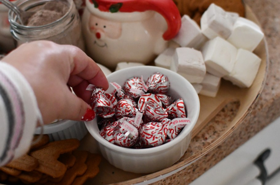 hand grabbing hershey hugs from a hot chocolate charcuterie board