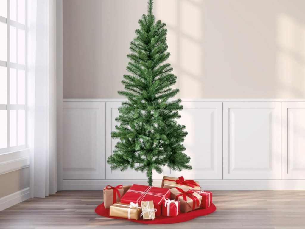 unlit artificial christmas tree in room surrounded by presents