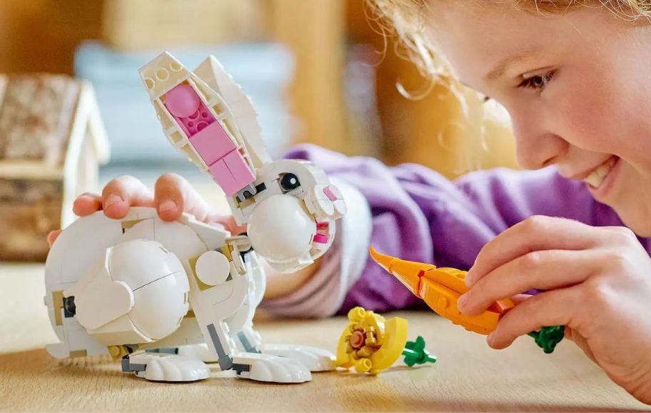 a little girl playing with a lego rabbit and lego carrot