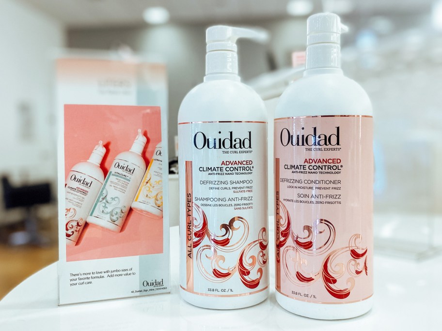 large white and pink bottles of Ouidad Shampoo & Conditioner on store shelf