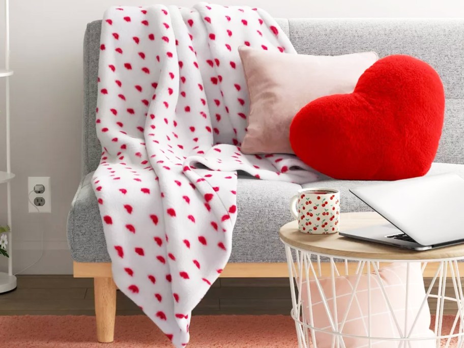 white blanket with red lips print draped over couch with throw pillows