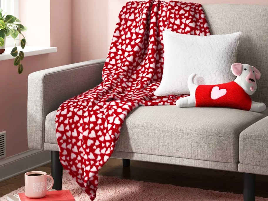 red and white heart print throw blanket draped over couch with throw pillows