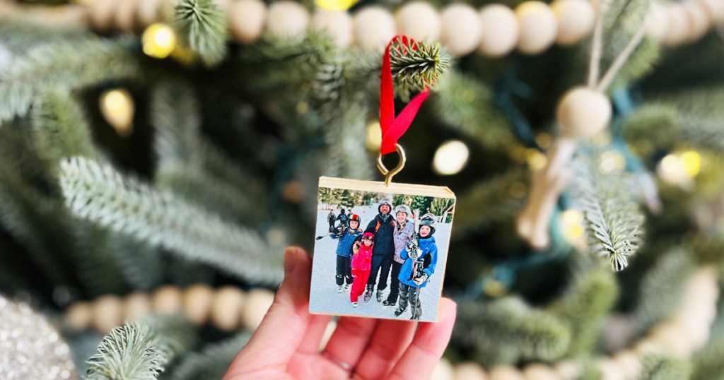 hand holding wood block ornament on christmas tree