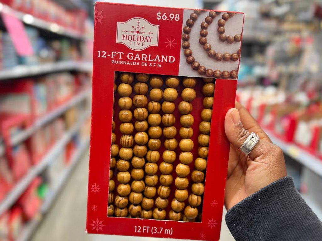 Hand holding up a box of wooden bead garland from Walmart