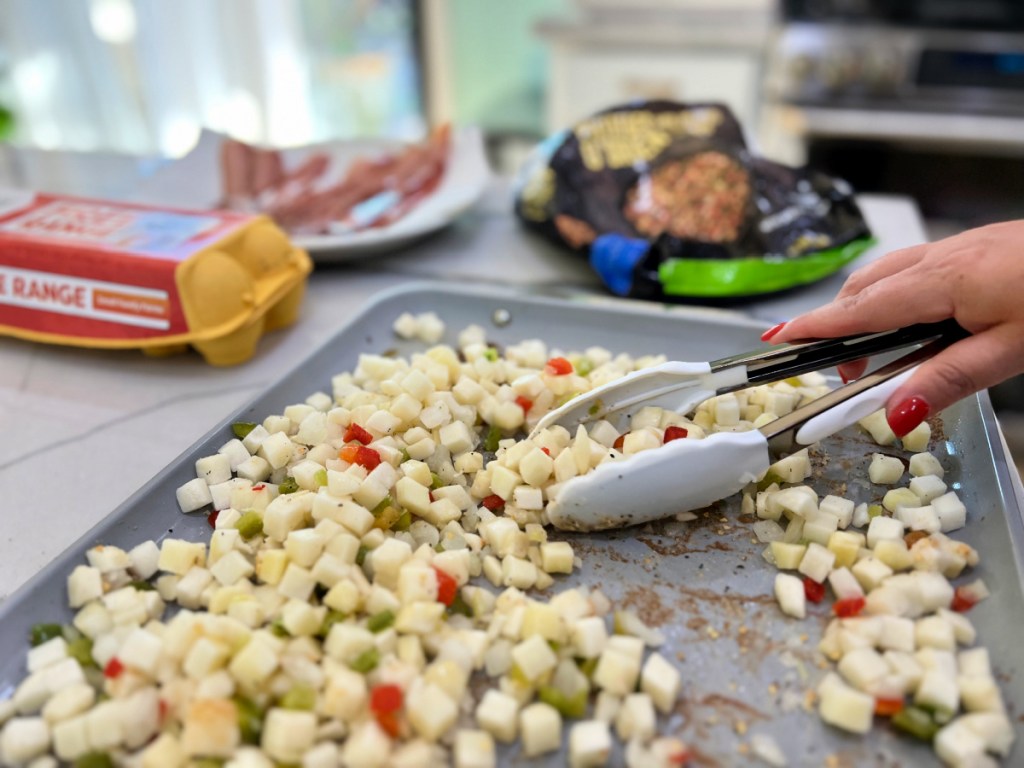 adding breakfast potatoes to a sheet pan