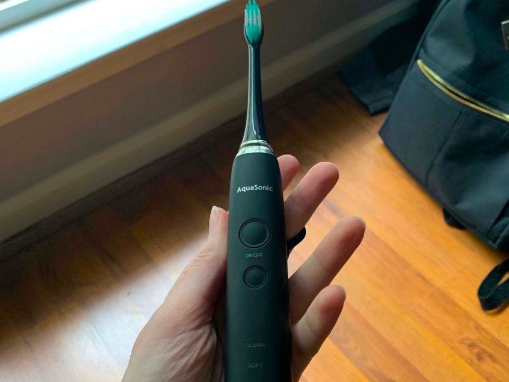 hand holding black aquasonic toothbrush