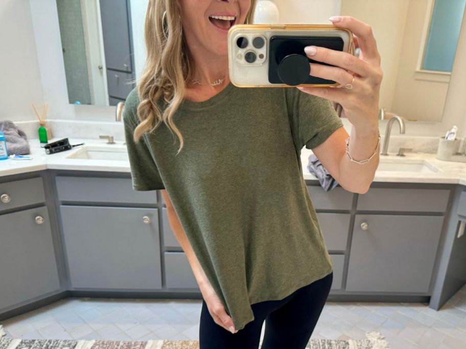 a woman wearing a dark heather green tee taking a selfie