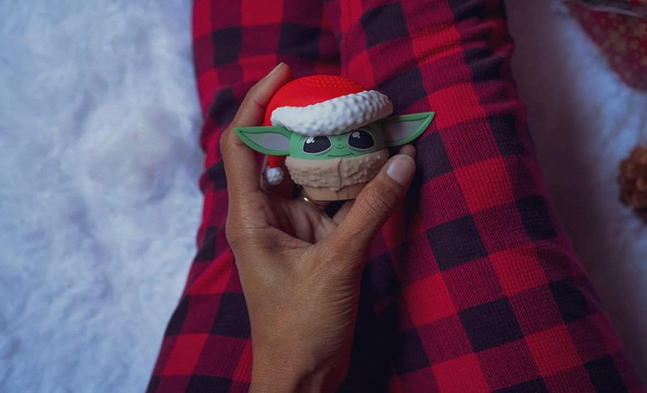 Person holding mini Star Wars speaker on laugh with red and black plaid pajama pants