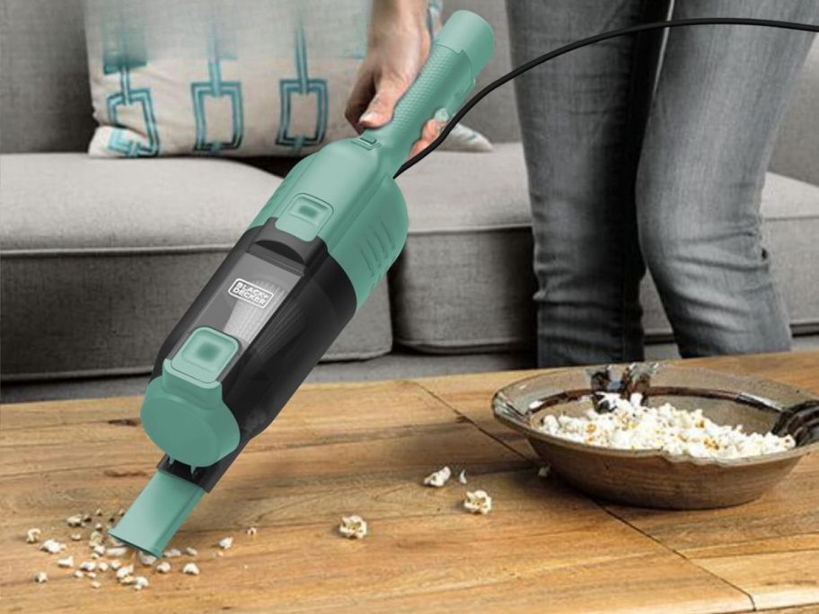 person using Black+Decker 3-in-1 Vacuum as a handhelf vacuum on a table picking up popcorn