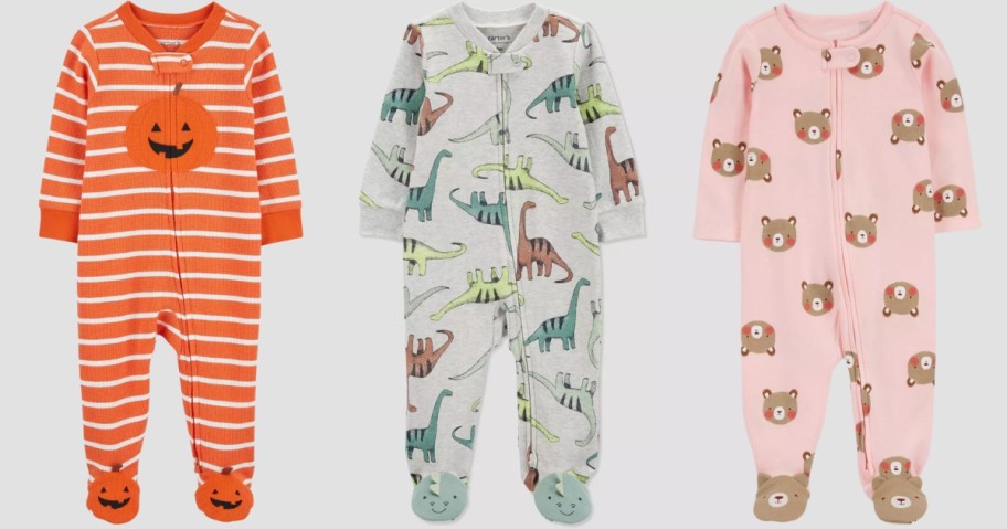 baby footed pajamas in orange stripes with a pumpkin, grey with dinosaurs, and pink with bears