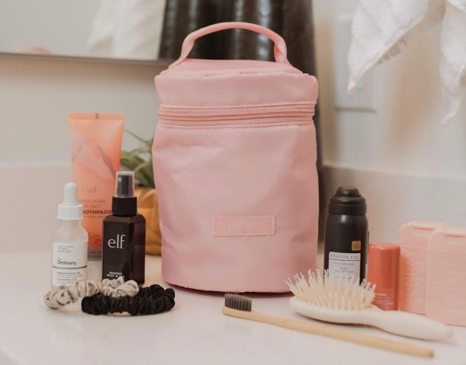 pink circular makeup bag on bathroom sink with cosmetic products