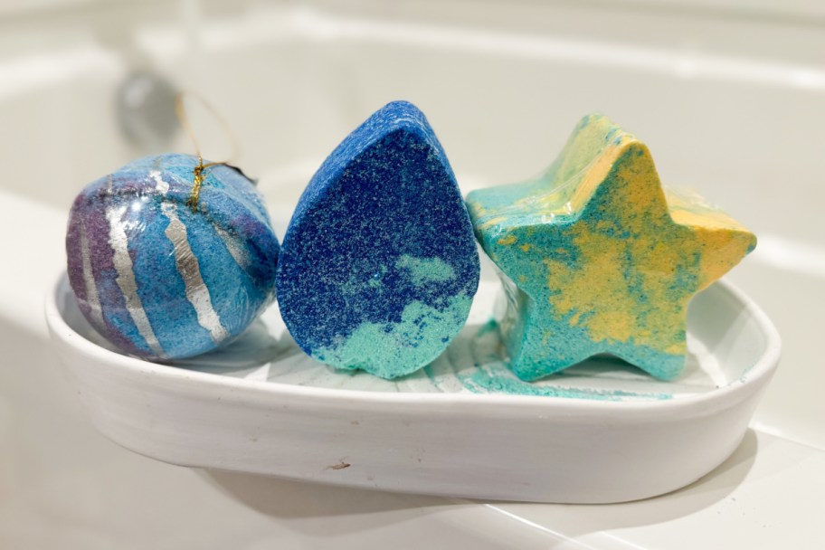 three bath bombs on edge of bath