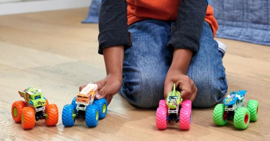 boy playing with Hot Wheels Monster Trucks Toy Trucks on floor