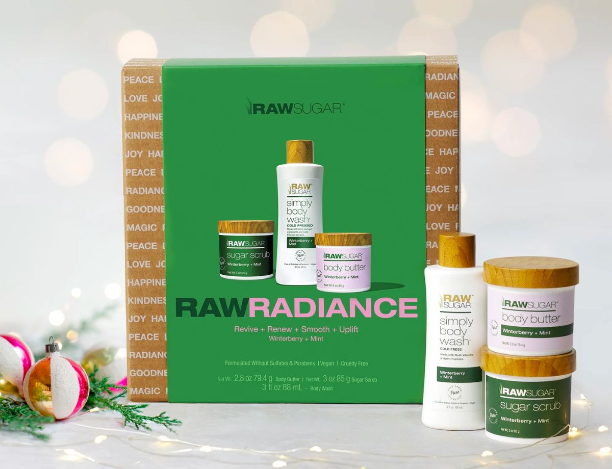 raw sugar radiance 3 piece skin care gift set next to 2 christmas tree ornament balls. 