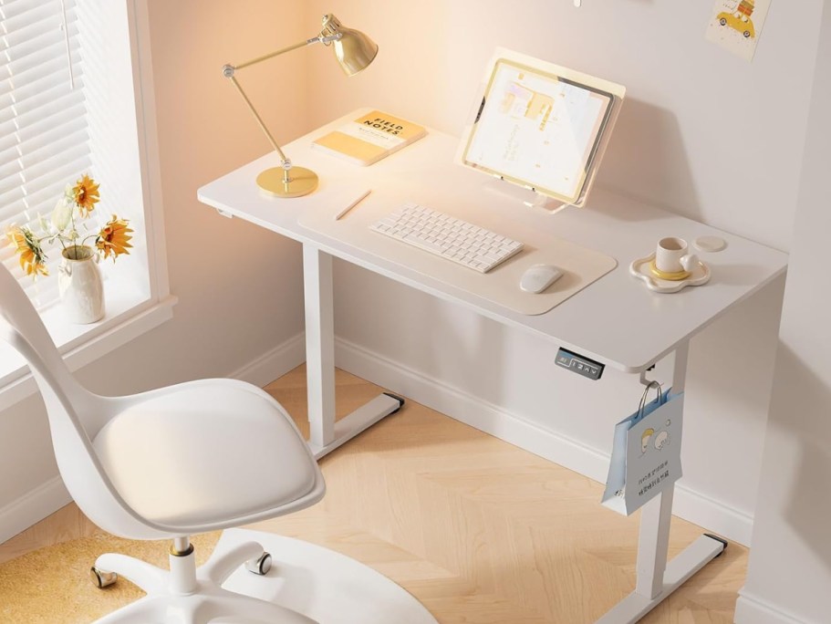 white electric standing desk with onlineputer and office accessories