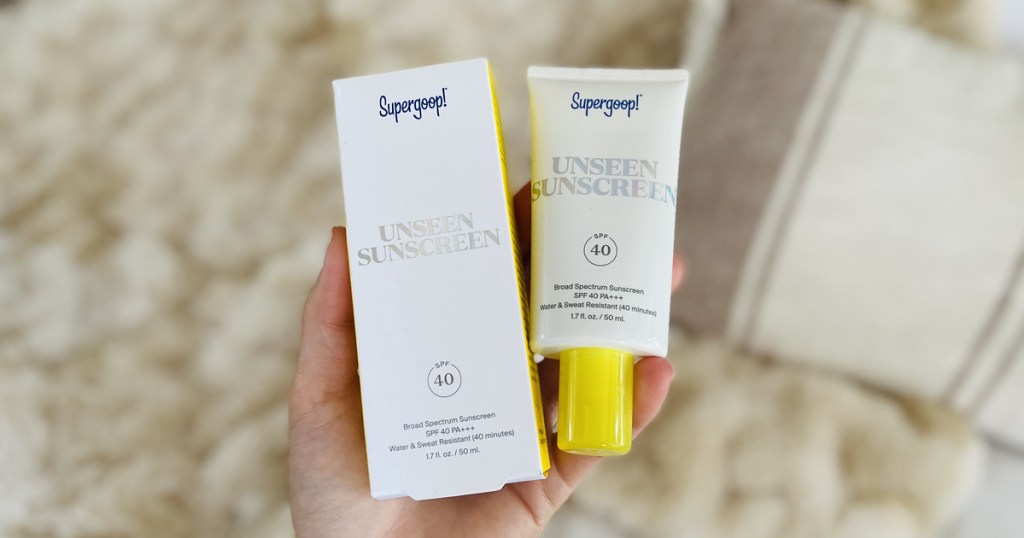 holding a box and tube of supergoop sunscreen