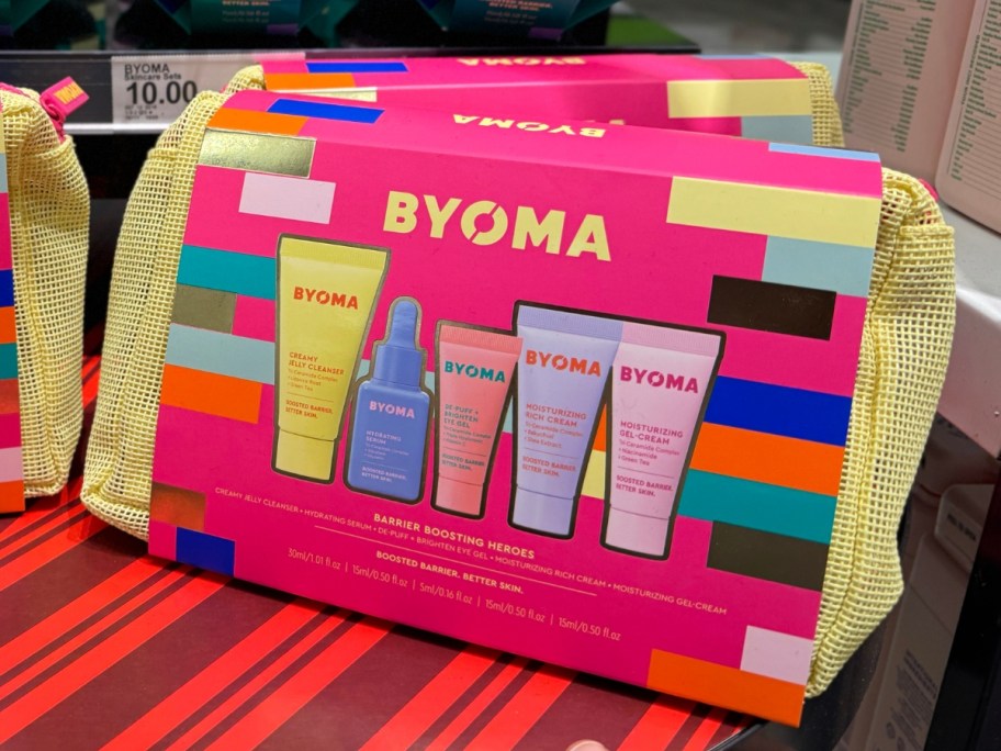 a yellow cosmetic bag with a pink paper label that shows a BYOMA Mini Heroes Intro Gift Set and products that are inside