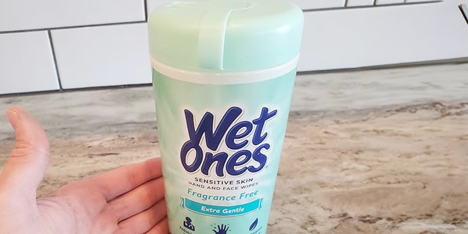 hand reaching for wet ones wipes container 