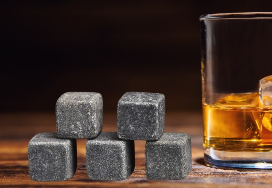 stack of whiskey stones on wood table with whiskey glass next to them