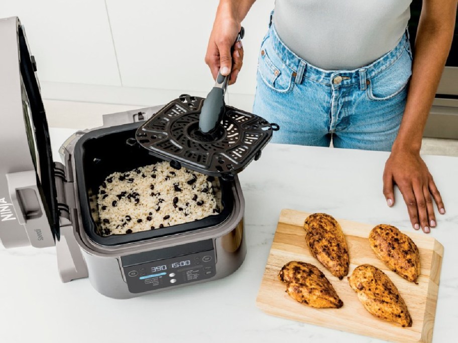 woman taking out grill part from ninja speed with rice and chicken