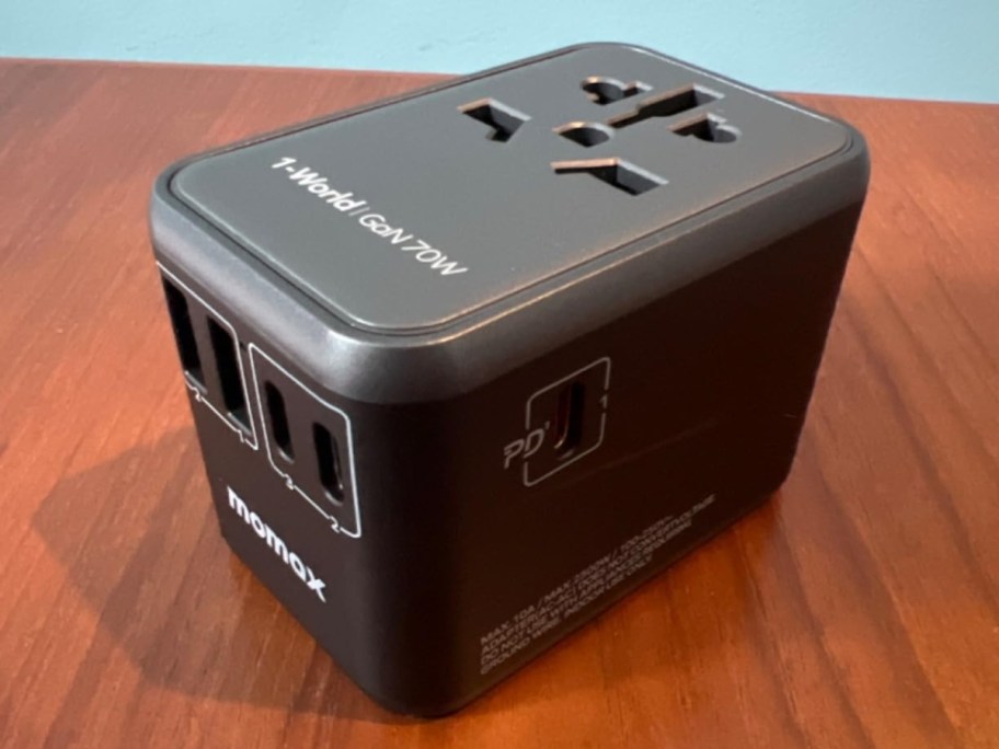 black MOMAX 100W Universal Travel Adapter sitting on a desk