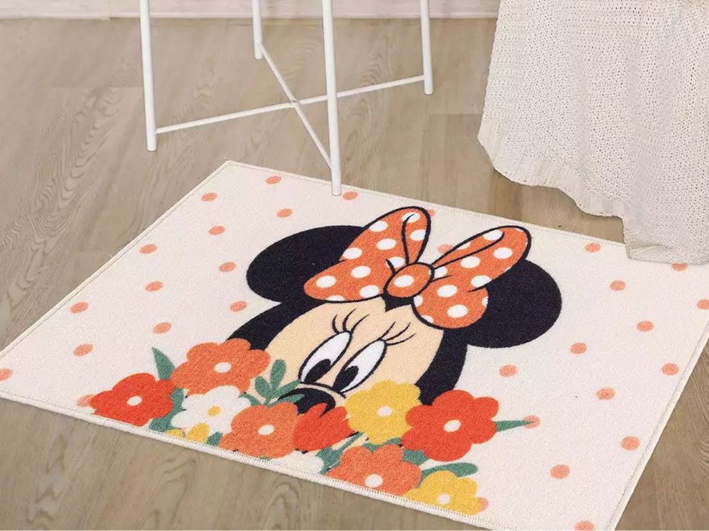 rug with Minnie Mouse, flowers and polka dots laying on floor by chair