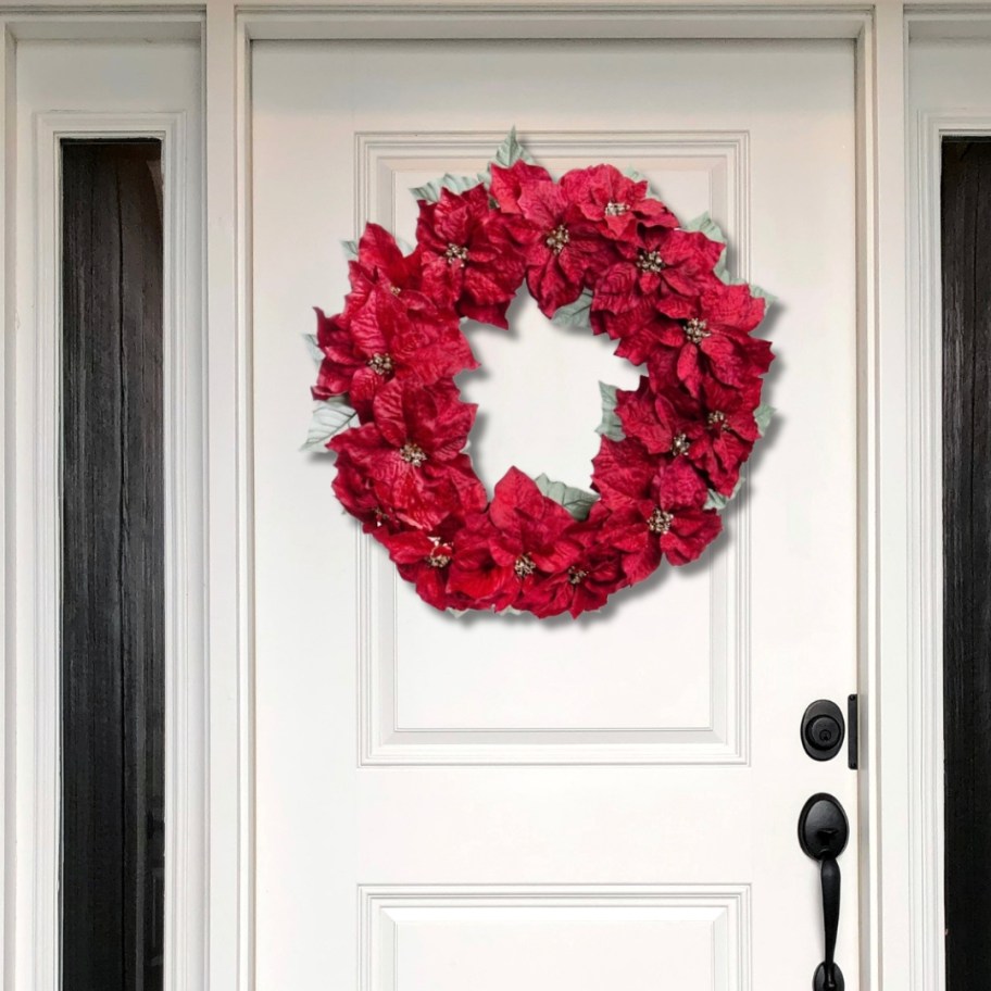 a red poinsettia wreath on a white door