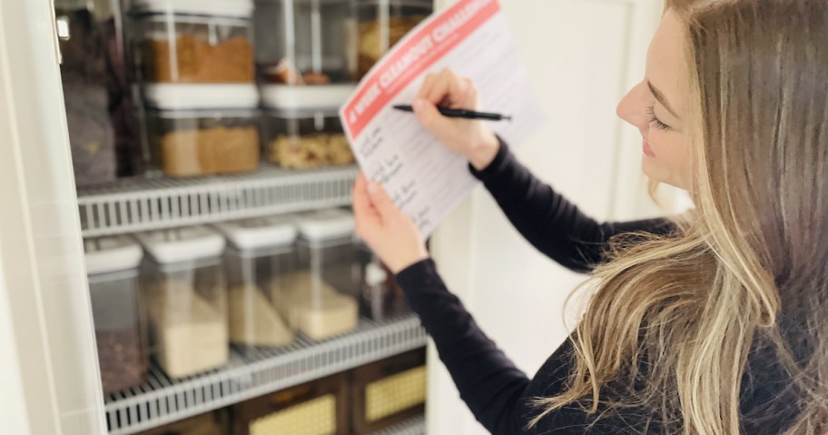 woman holding paper in front of organized pantry