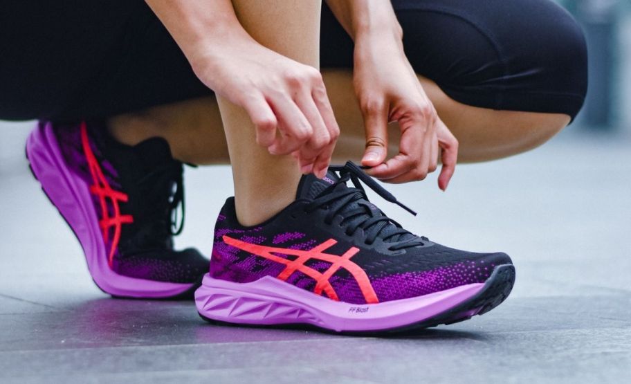 a woman kneeling down and tying a shoe lace 