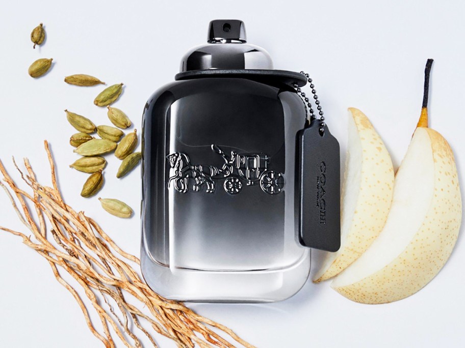 black and white coach perfume bottle near sliced pears