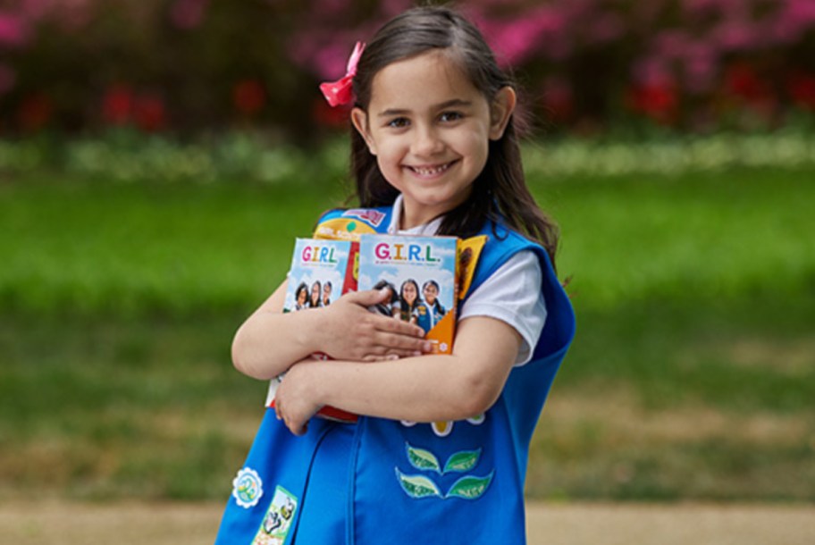 A girl scout holding cookies