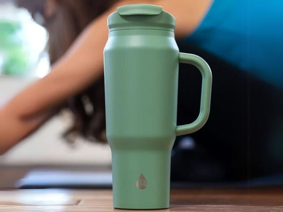 Tal 30oz tumbler in sage green, woman doing yoga behind the tumbler