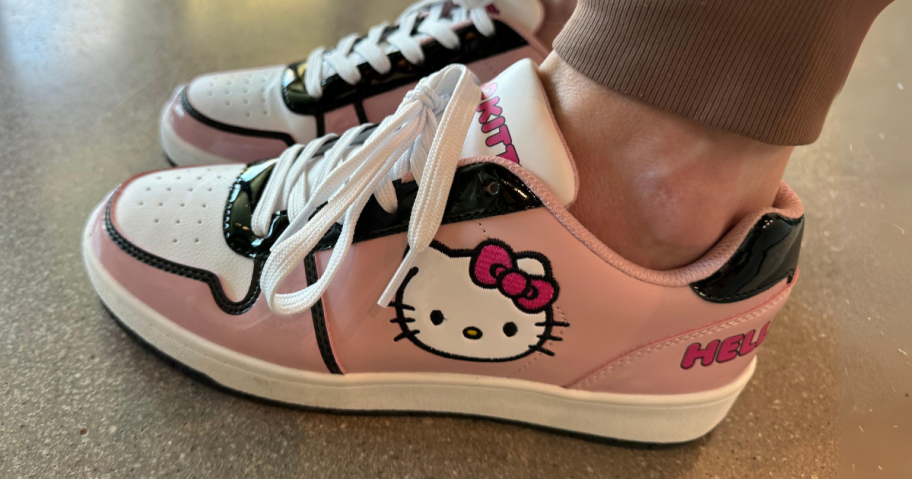 women's feet wearing a pair of Hello Kitty Sneakers in pink black and white