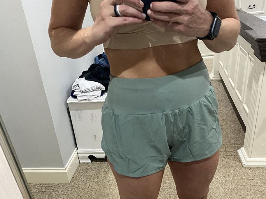 front view selfie of a woman trying on a pair of jogging shorts