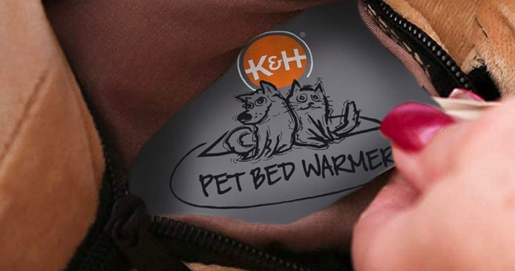 a womans hand displaying a K&H pet bed warmer inserted into a ped bed liner