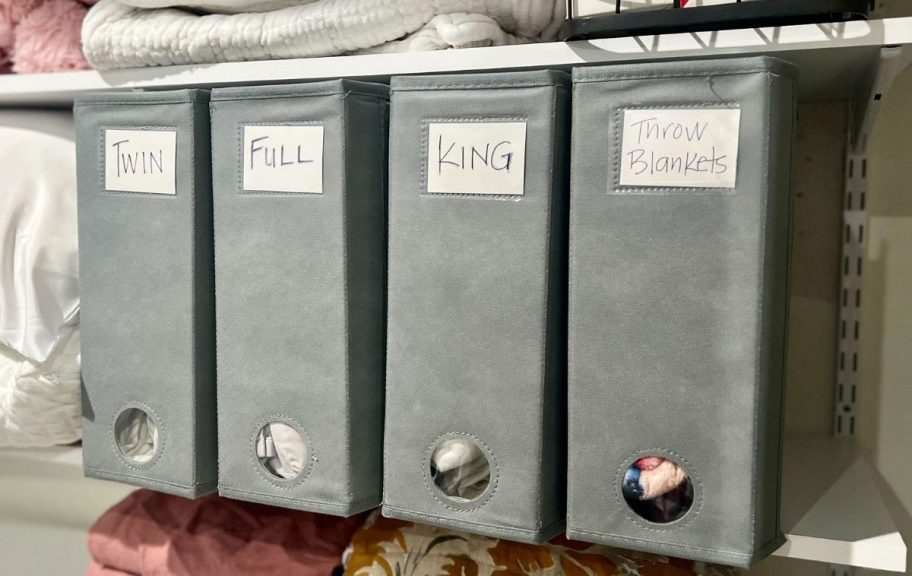 A closet with 4 sheet organizer cubes inside for different size sheets and throw blankets