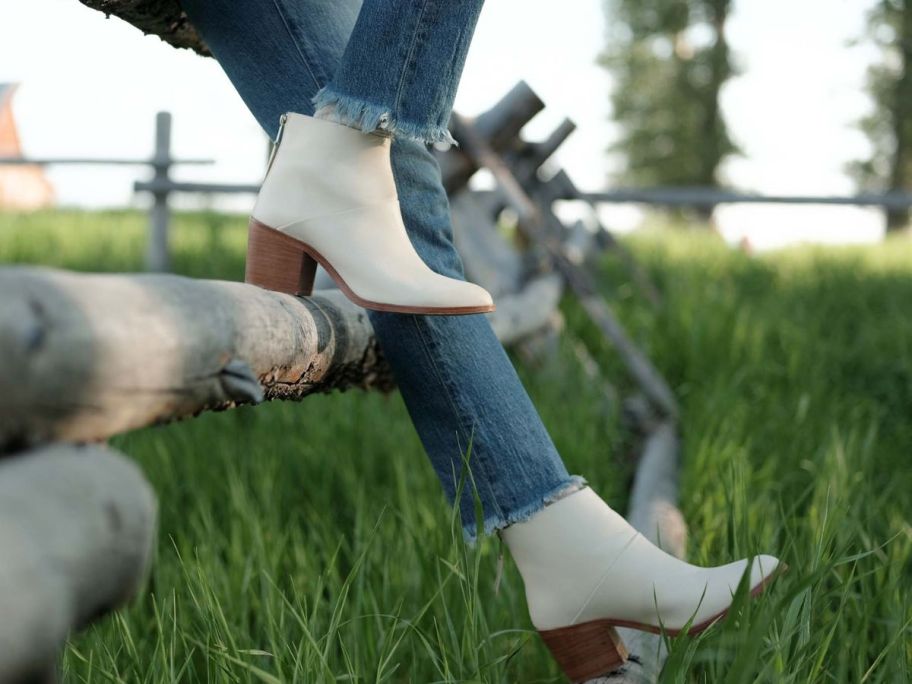 woman sitting on a fence wearing Nisolo Dari Boots