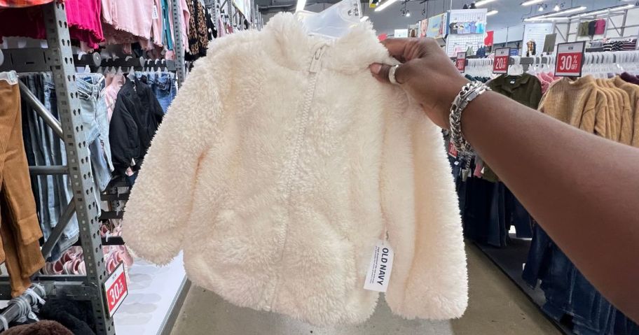 Hand holding an Old Navy Fleece Baby Jacket on a hanger