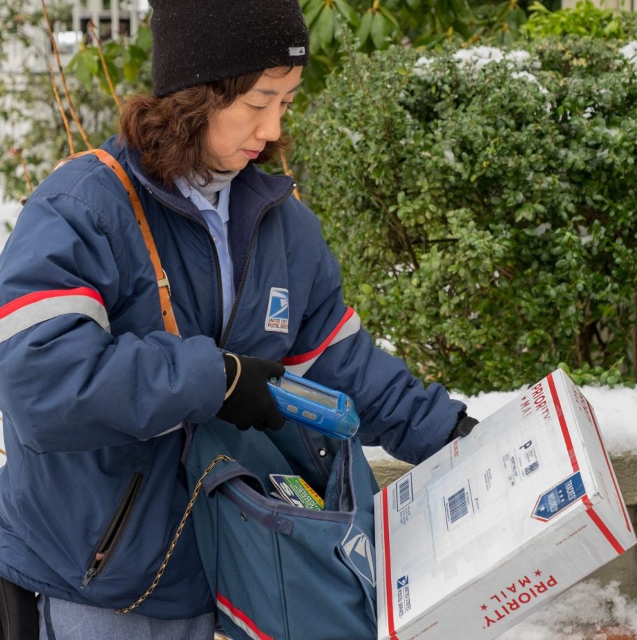 A USPS postal worker delivering priority mail