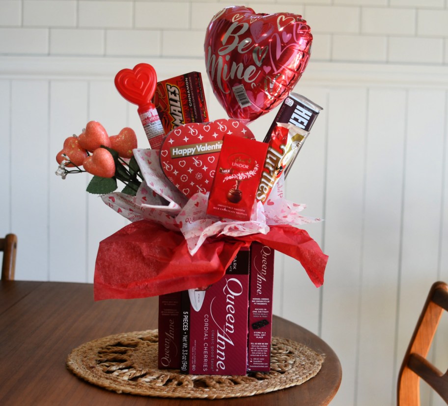 A Valentine's Day Candy Bouquet on a table with a balloon and chocolate covered cherries