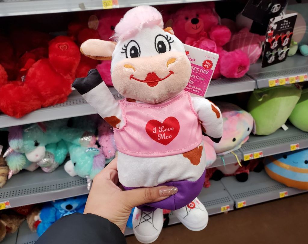 a womans hand displaying a white and pink cow valentine day plush doll