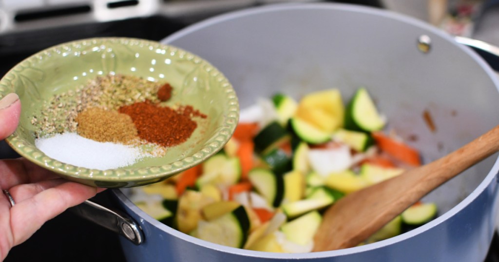 adding seasonings to pot of soup