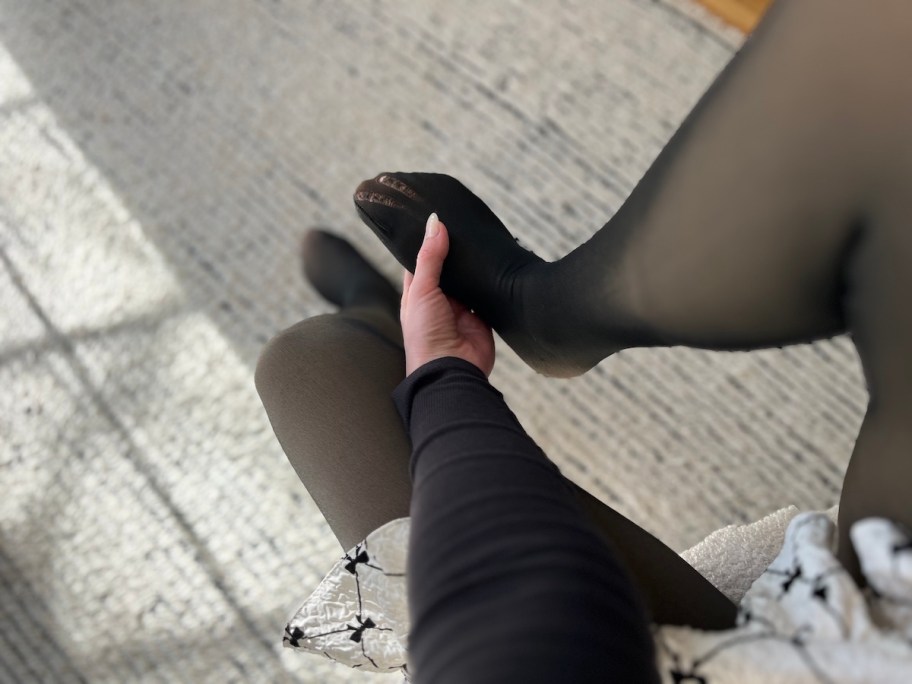 hand holding foot with run in black tights