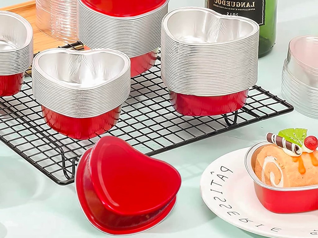 heart shaped red tins with lids, and rose petals on table