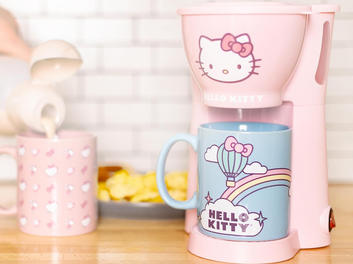 pink hello kitty coffee maker with blue coffee mug on table with pink mug 