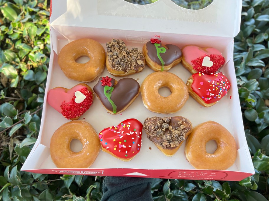 hand holding box of valentines doughnuts