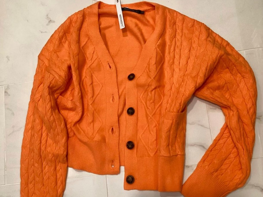 orange crop cardigan laying on table