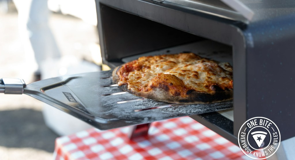 paddle pushing out pizza from pizza open with one bite symbol